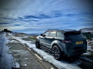 A range rover on the snowy road with a blue sky and frost winter protection
