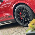 "Precision-painted red brake calipers on a Porsche, giving the vehicle a customized and aggressive appearance. The high-temperature enamel paint ensures durability and shine."